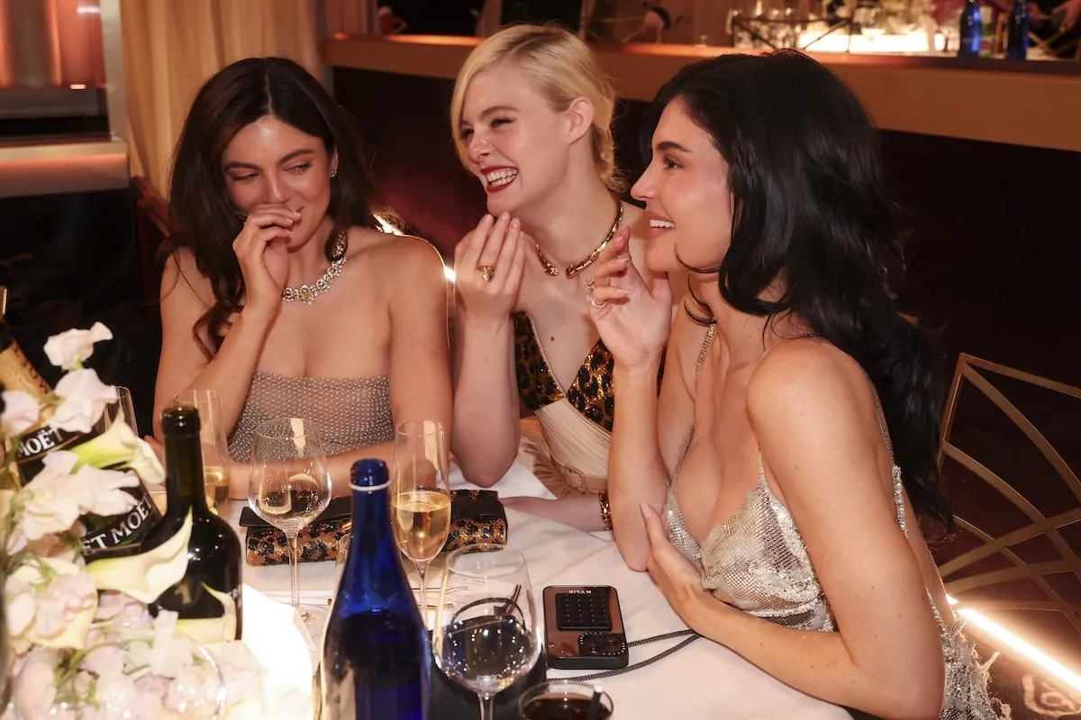 Sitting together at their table, Monica Barbaro, Elle Fanning, and Kylie Jenner laugh at the 82nd Annual Golden Globes