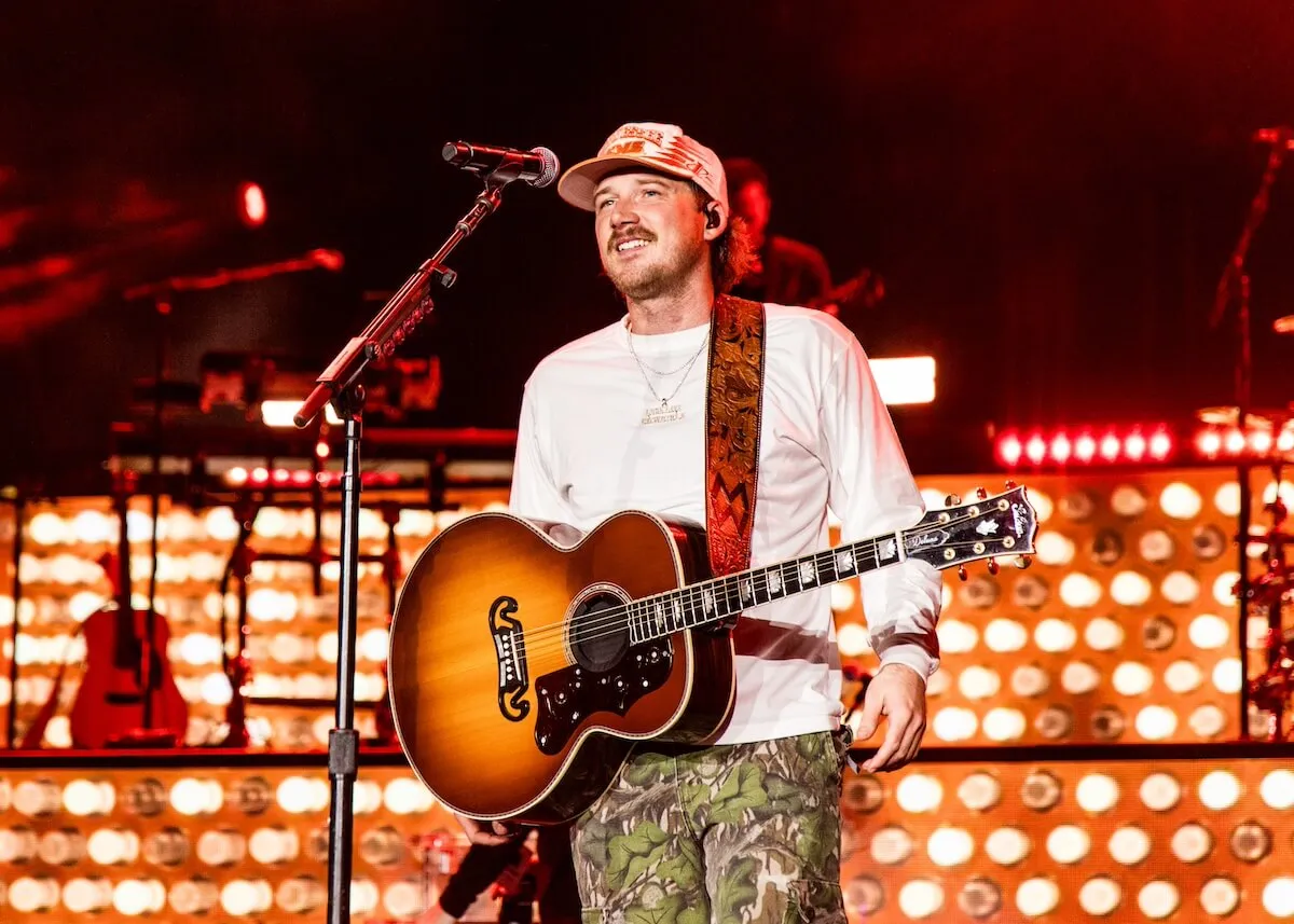 Morgan Wallen standing on a stage with a guitar