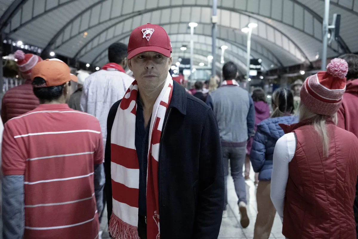 JD (Todd Lasance) wearing a red cap and scarf in the 'NCIS: Sydney' Season 2 premiere