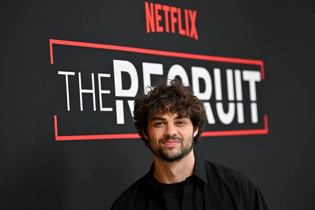 Noah Centineo poses on the red carpet in front of a step-and-repeat featuring 'The Recruit'