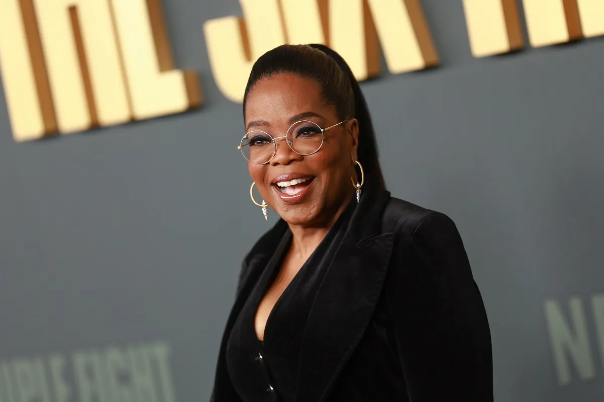 Oprah Winfrey posing at the premiere of 'Six Triple Eight' in a black suit.