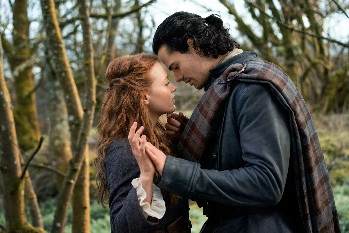 Red-haired woman and dark-haired man from 'Outlander: Blood of My Blood' touching their foreheads together