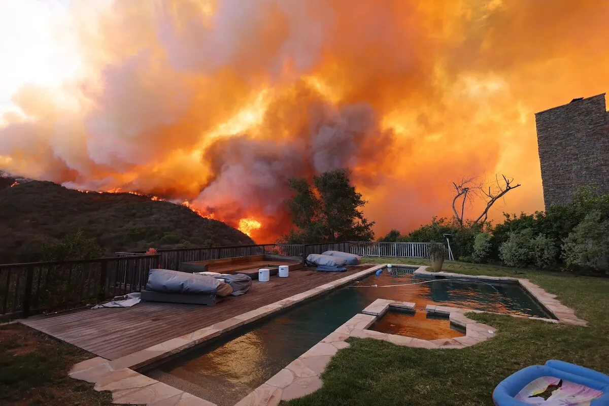 A swimming pool sits in the shadows of the Pacific Palisades fire