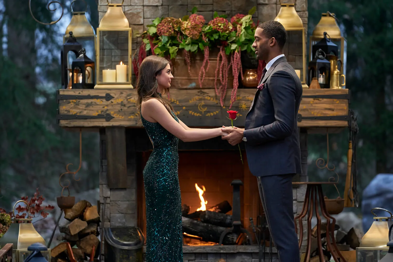 Rachael Kirkconnell and Matt James holding hands and facing each other during 'The Bachelor' Season 25 finale. Rachael is wearing a green dress and Matt is wearing a suit while holding a rose.