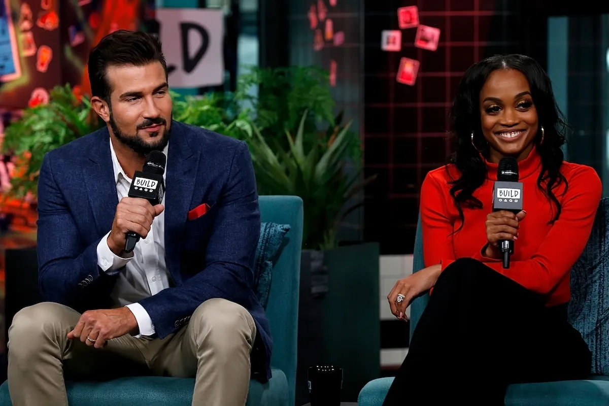 Sitting together on a stage, Bryan Abasolo and Rachel Lindsay hold microphones while they discuss The Bachelorette in 2019