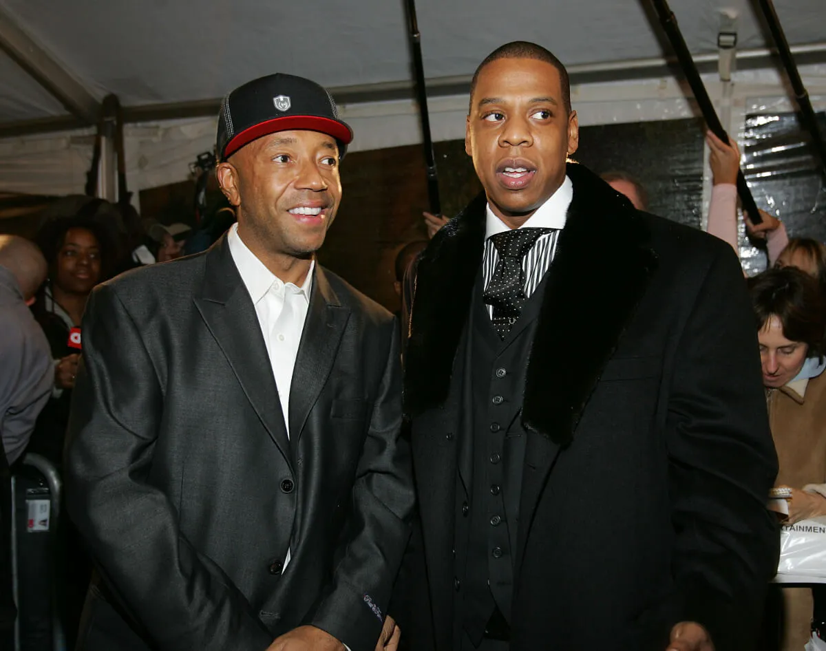 Russell Simmons and Jay-Z stand together. Simmons wears a hat.