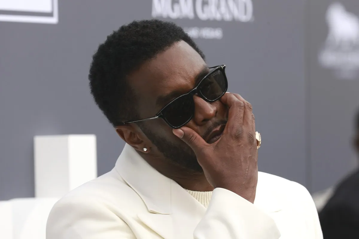 Sean Diddy Combs posing in a white suit at the 2022 Billboard Music Awards.