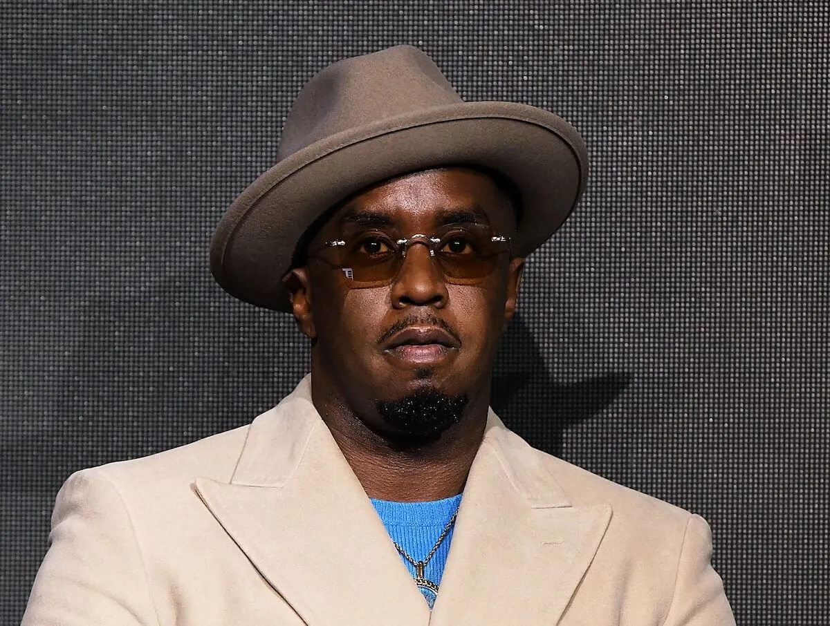 Sean 'Diddy' Combs wears a fedora, tan jacket, and sunglasses.