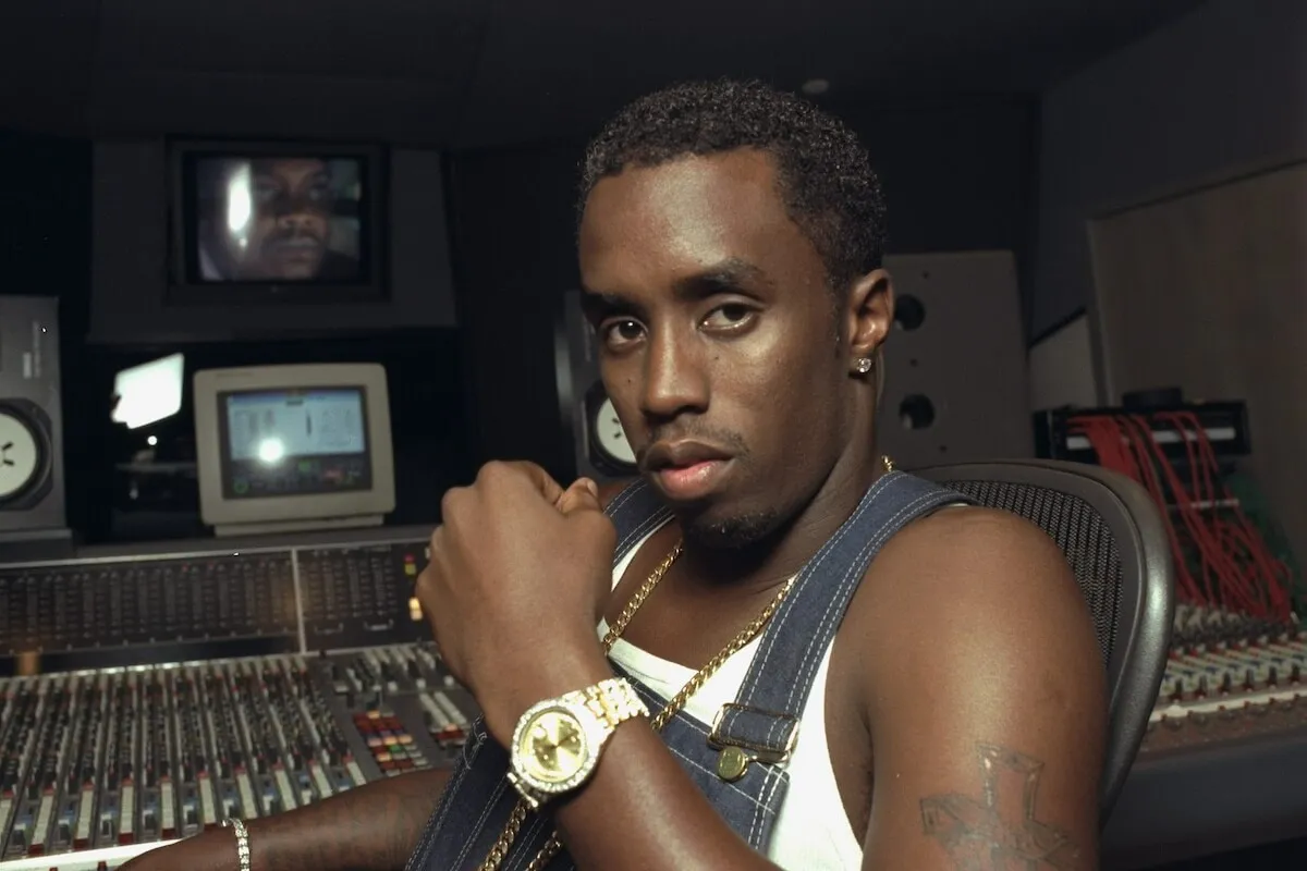 Sean 'Diddy' Combs wears overalls and sits in a recording studio.