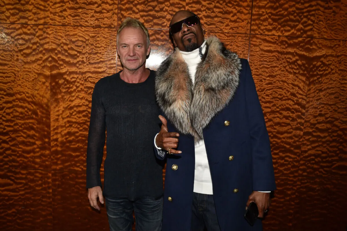 Sting wears black and stands with Snoop Dogg, who wears a coat with a large fur collar.