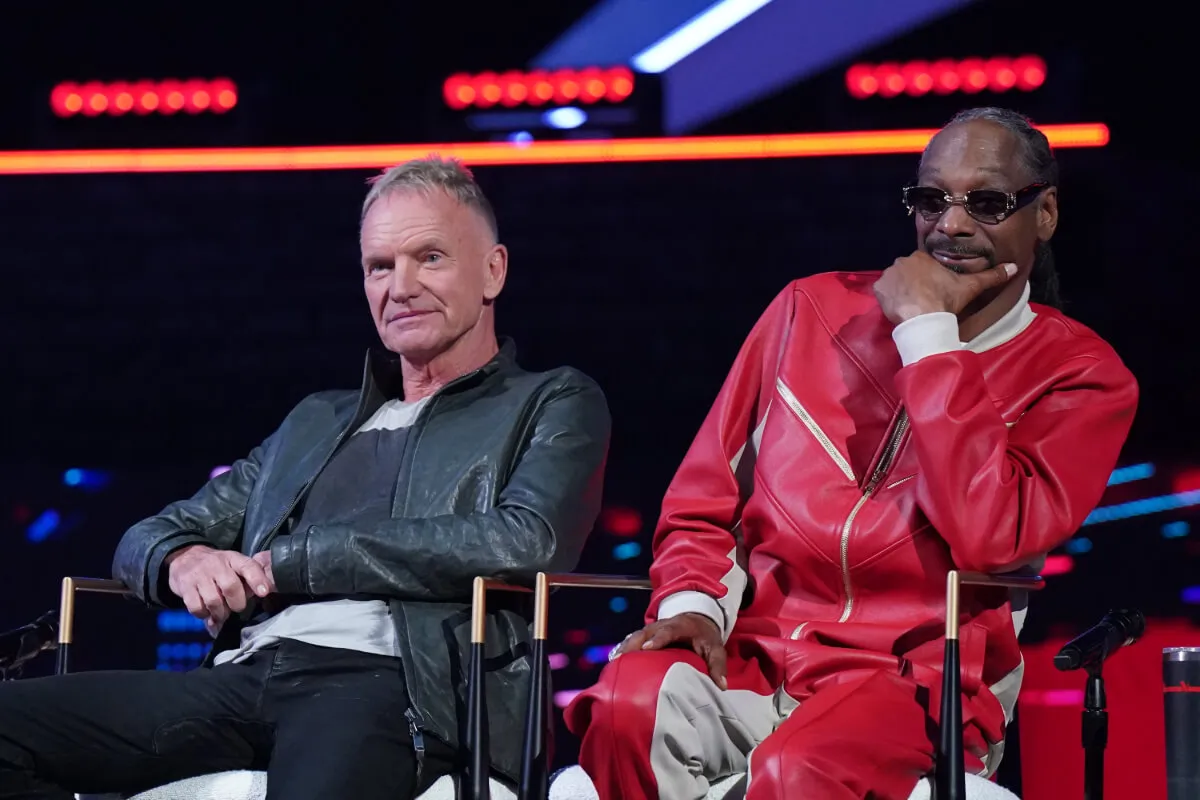 Sting wears black and sits in a chair next to Snoop Dogg, who wears all red, on 'The Voice.'