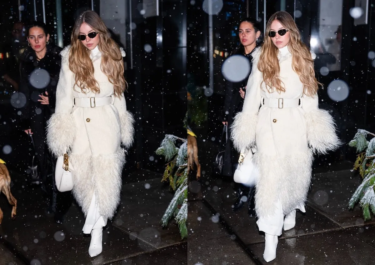 Wearing a white shearling coat, Sydney Sweeney smiles at paparazzi in NYC