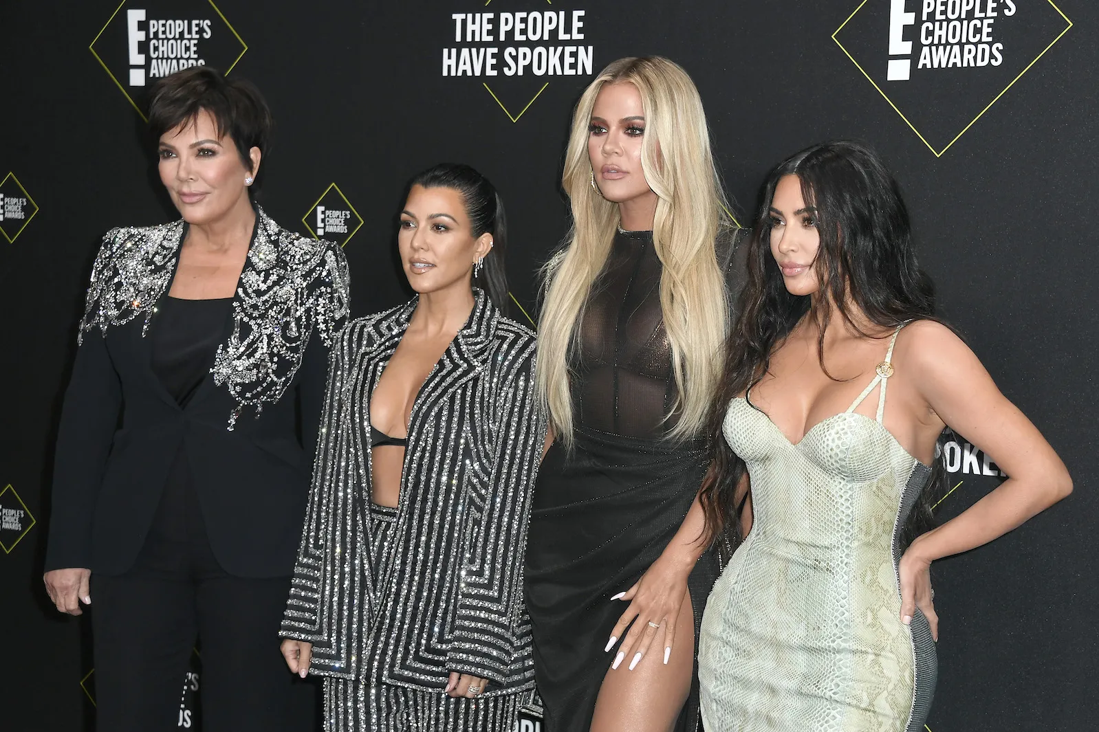 Kris Jenner, Kourtney Kardashian, Khloe Kardashian, and Kim Kardashian standing side by side and posing at an event in 2019