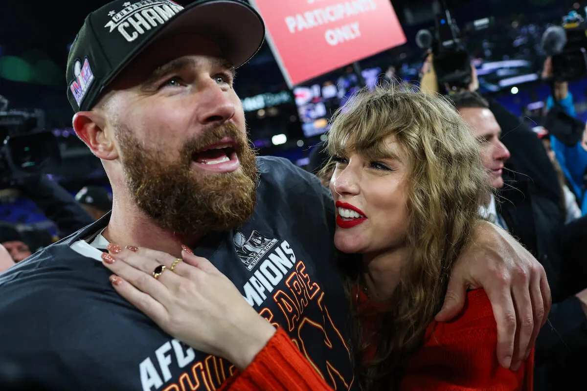 A close-up of Travis Kelce after a Kansas City Chiefs win with Taylor Swift staring up at him and smiling. She has her arm on his chest.