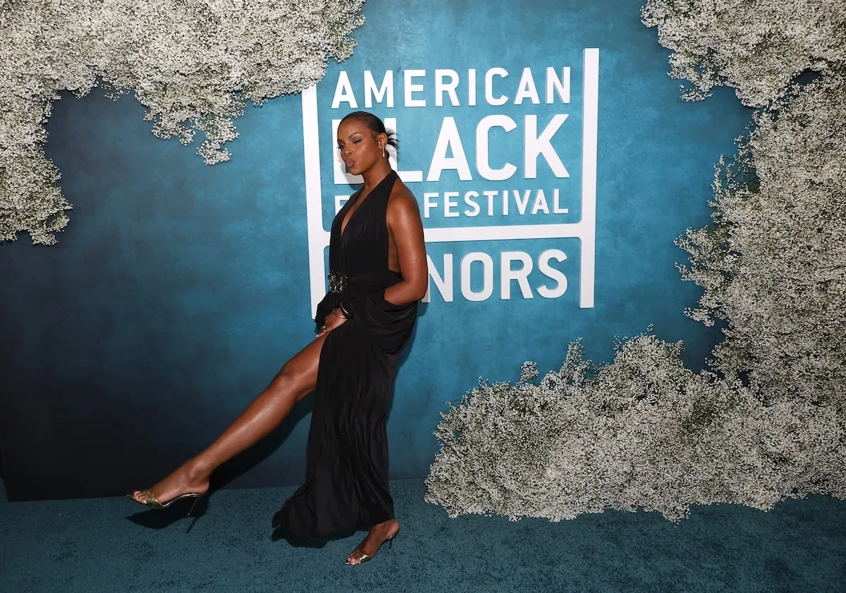 Wearing a black gown with a plunging necklace, Tika Sumper kicks her foot out while walking the red carpet before the American Black Film Festival