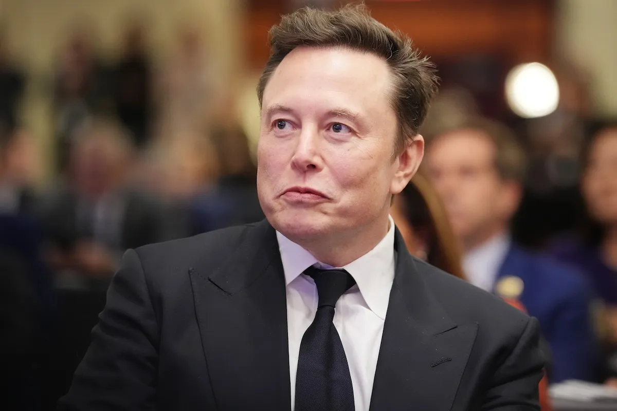 Elon Musk dressed in a suit, looking rich