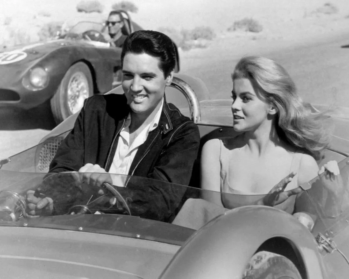 A black and white picture of Elvis driving a car with Ann-Margret next to him.