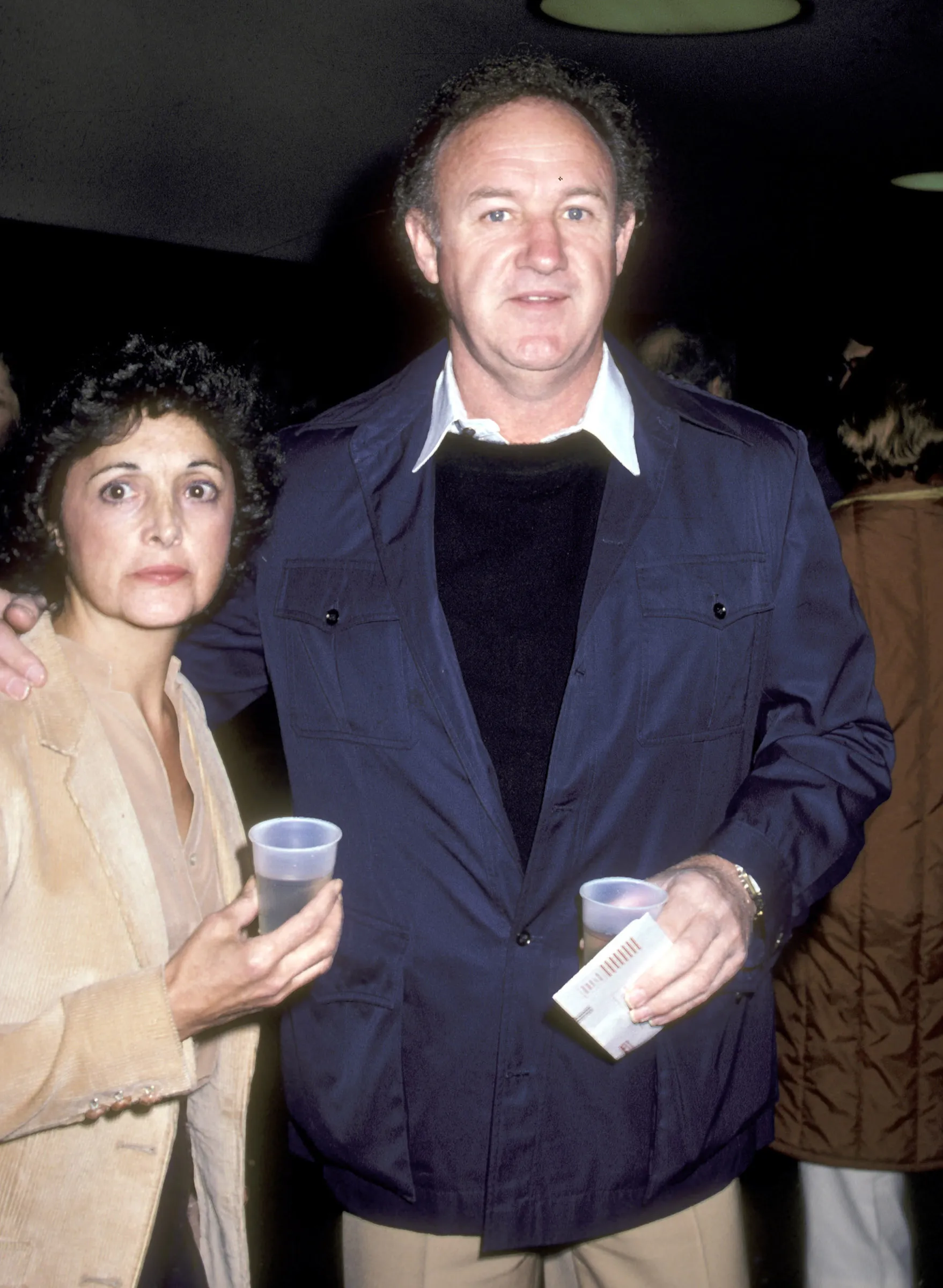 Gene Hackman and Faye Maltese standing next to each other against a dark background