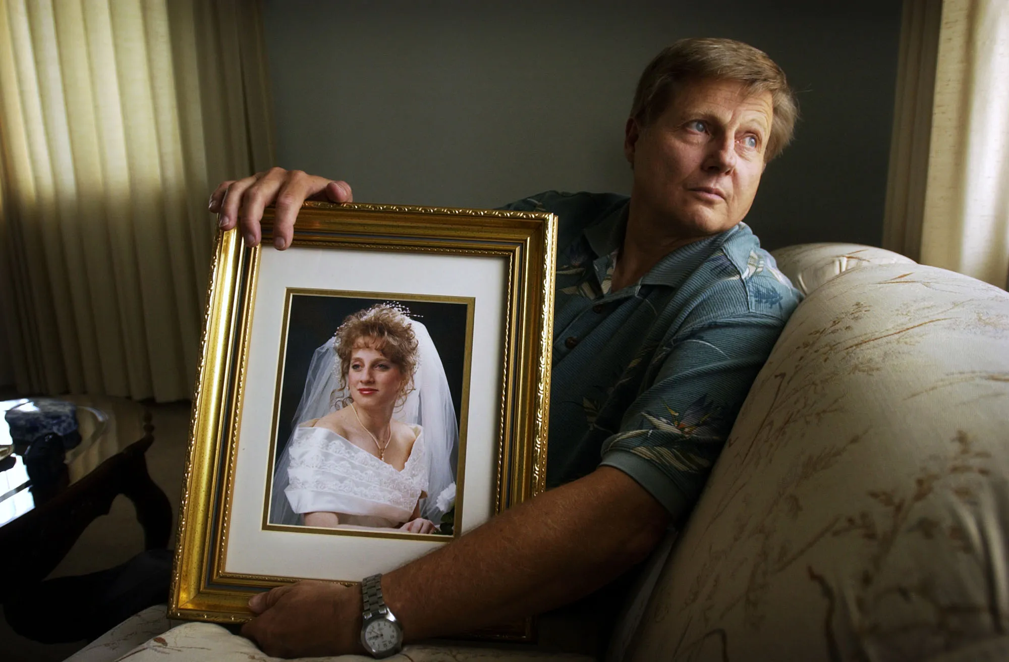 Dave Springer holds a portrait of his daughter Heather DeWild in her wedding dress