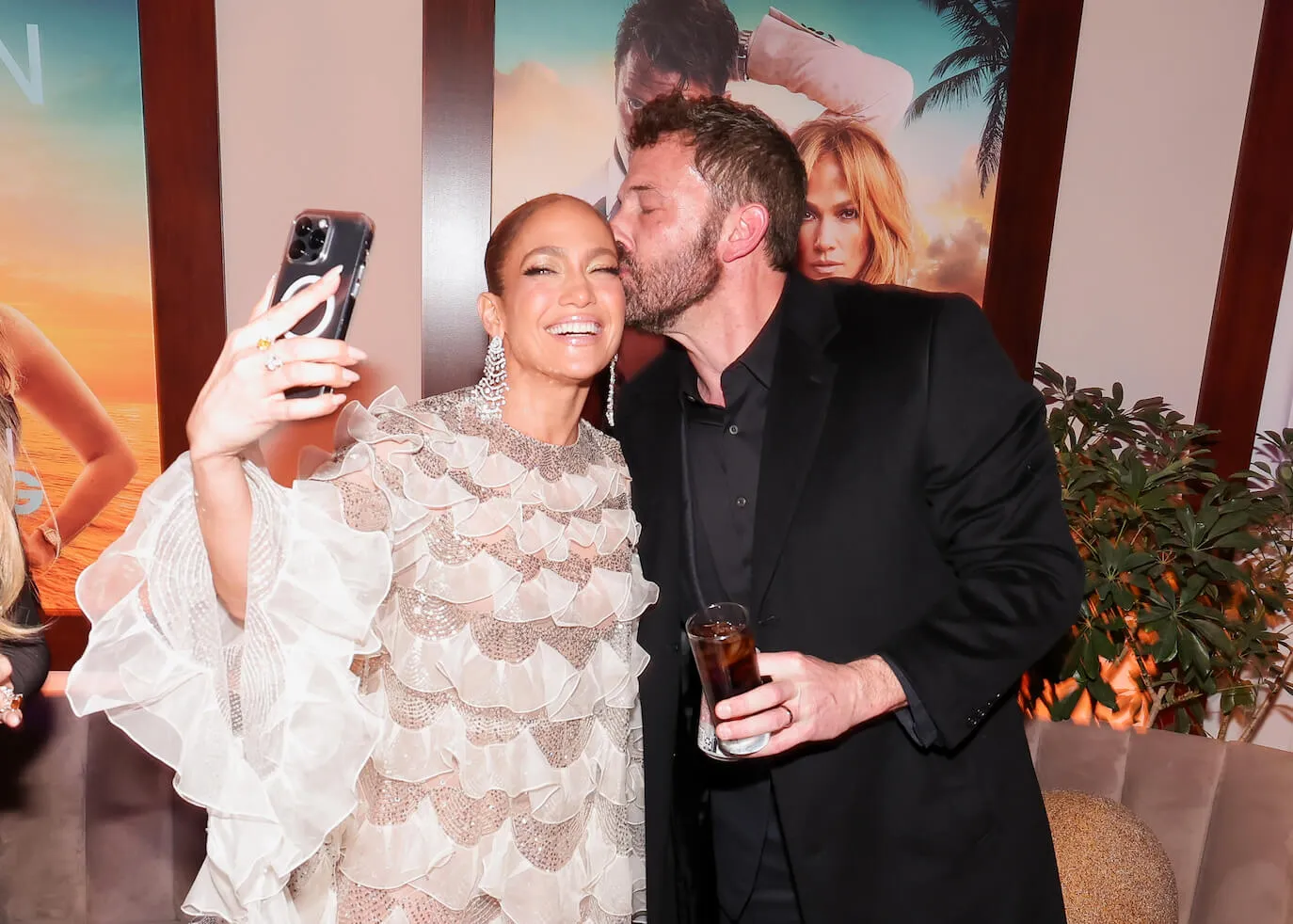 Jennifer Lopez taking a selfie and smiling while Ben Affleck kisses the side of her head