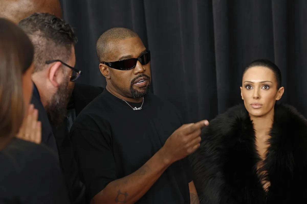 Kanye West pointing at Bianca Censori, who is staring straight ahead