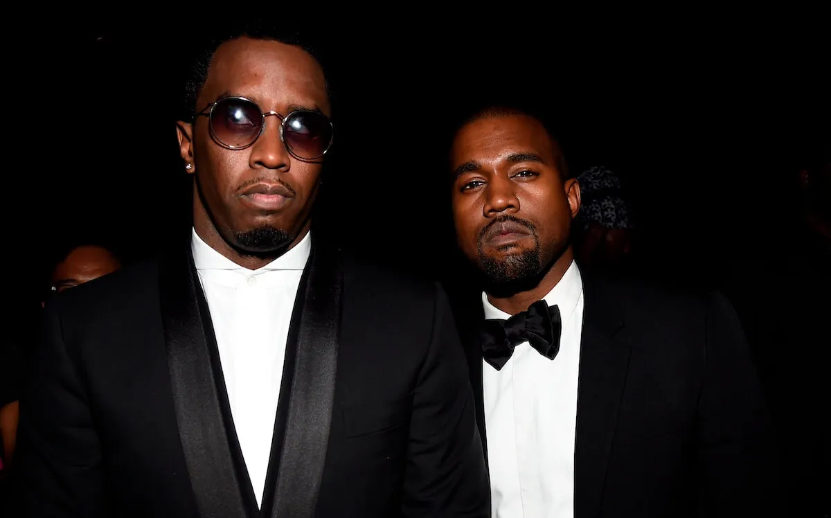 Sean 'Diddy' Combs and Kanye West stand together. Combs wears sunglasses and a suit, and West wears a tuxedo.