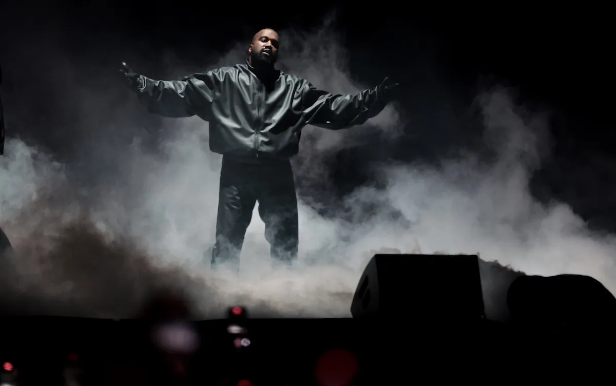 Kanye West with his arms held out to his sides surrounded by fog