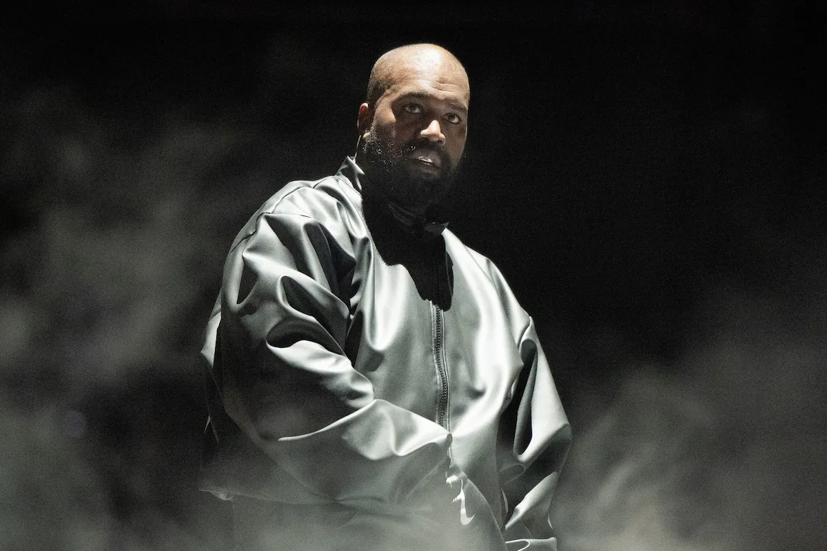 Kanye West, dressed in black and surrounded by fog, on stage in 2024