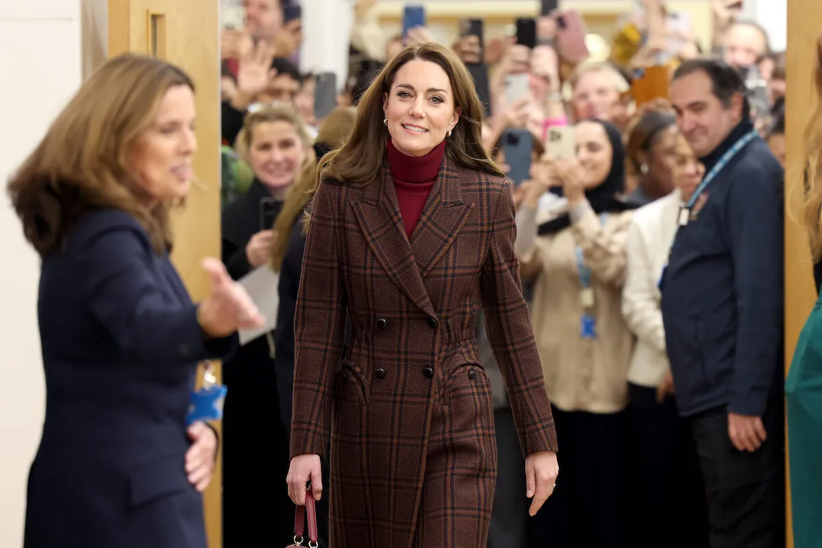 Kate Middleton, who no longer wants to talk about her clothes publicly, walks down a hallway.