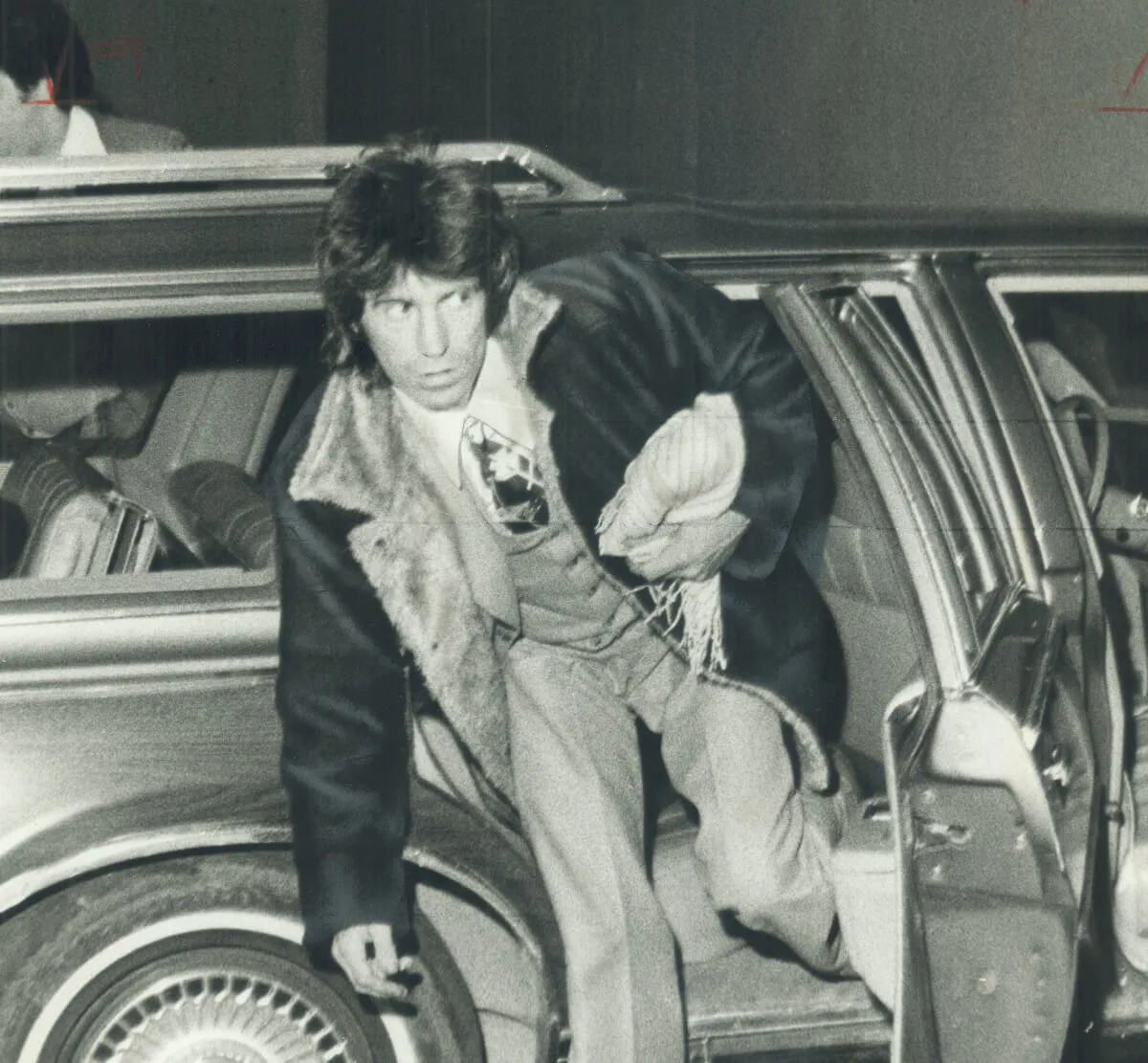 A black and white picture of Keith Richards exiting a car after his trial.