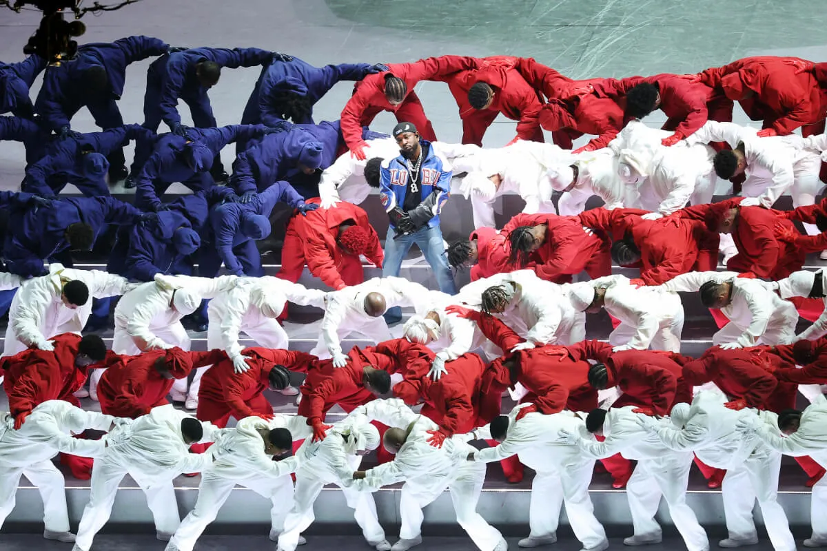 Kendrick Lamar stands in the center of dancers arranged to look like an American flag.