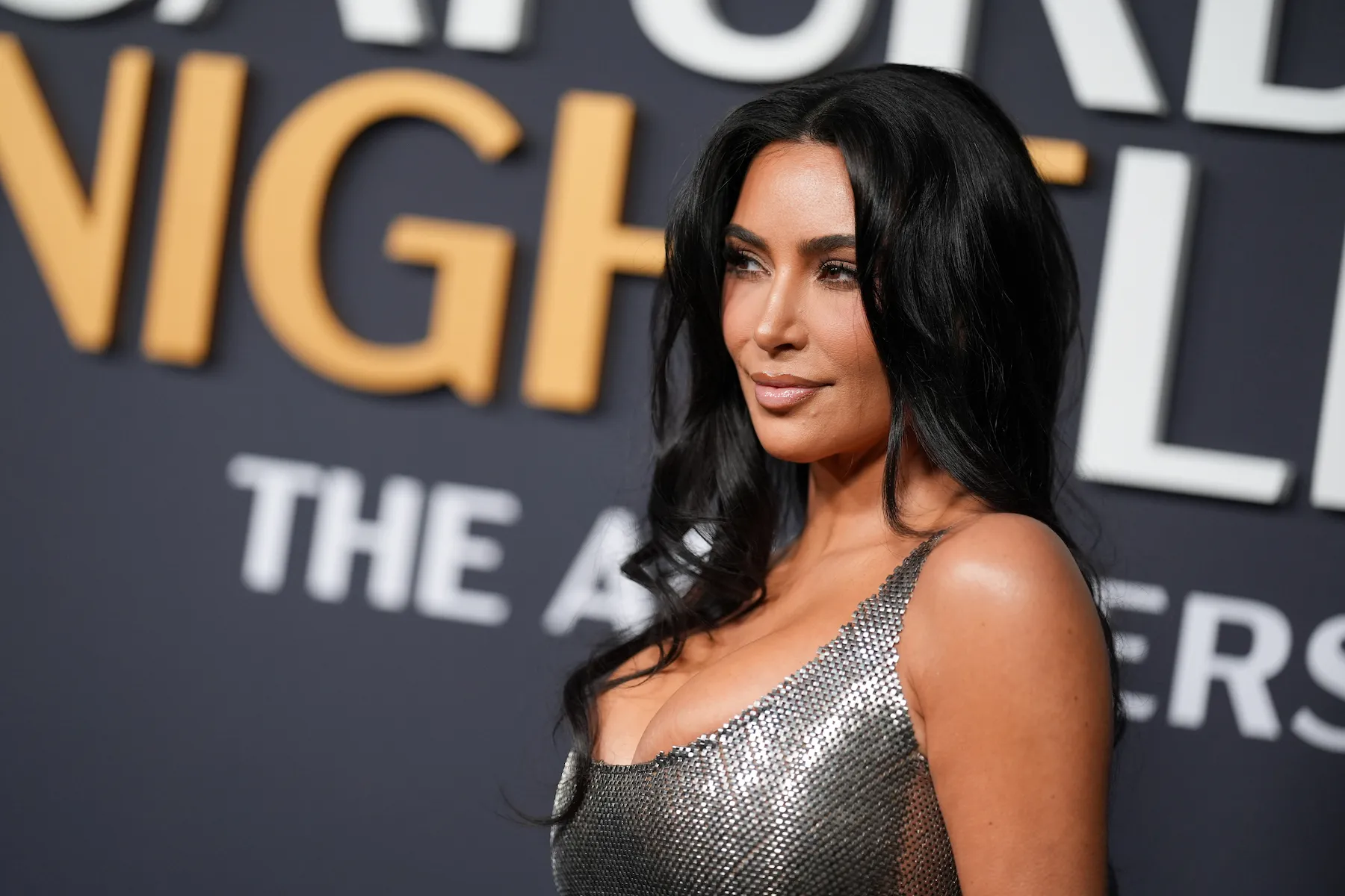 A side profile of Kim Kardashian smiling in a low-cut silver dress at 'SNL50'