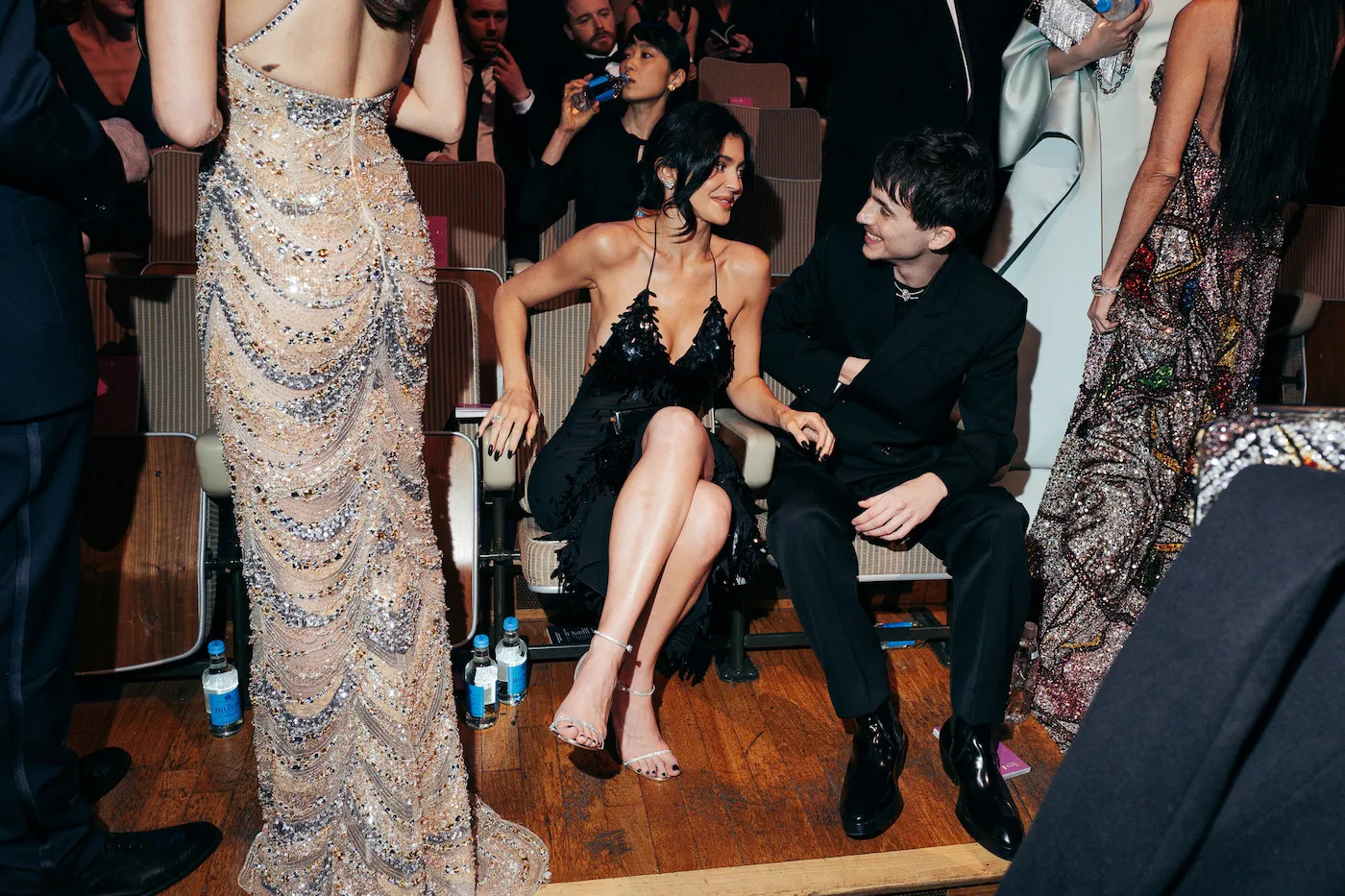 Kylie Jenner and Timothée Chalamet sitting next to each other at the BAFTAs in 2025. Jenner is wearing a black dress and Chalamet is wearing a black suit.