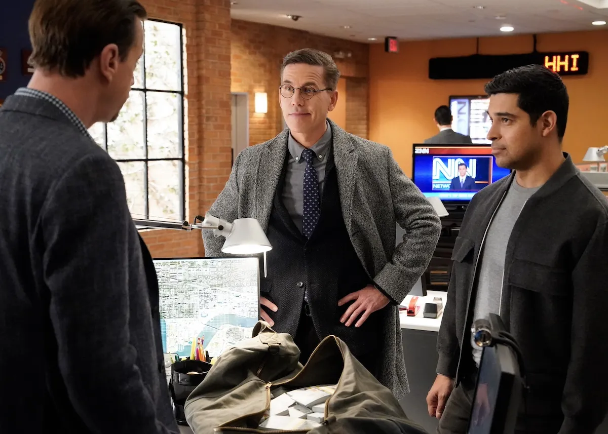 Three men standing around a desk and talking in 'NCIS' Season 22