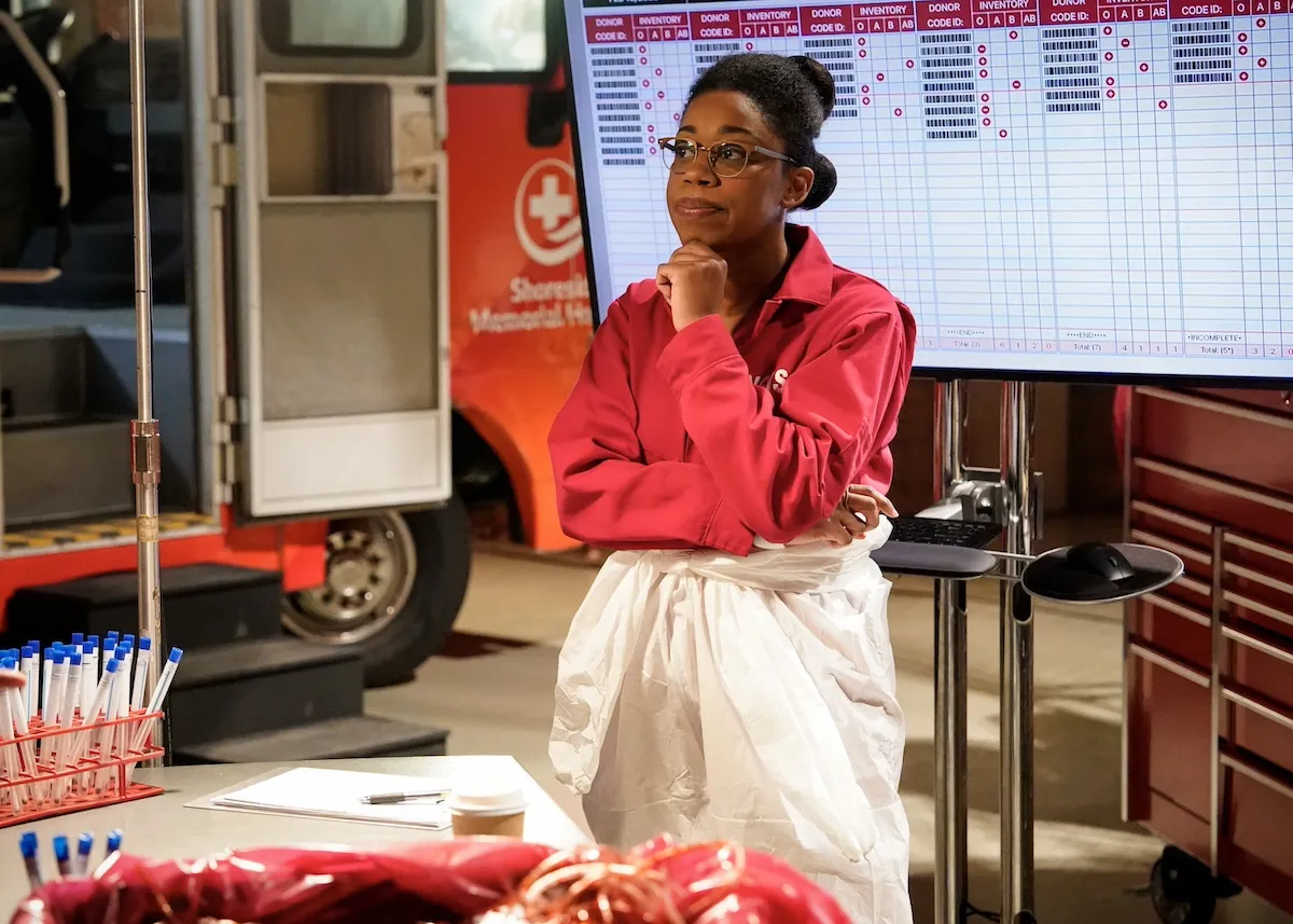 Diona Reasonover, wearing a red blouse, in 'NCIS' Season 22