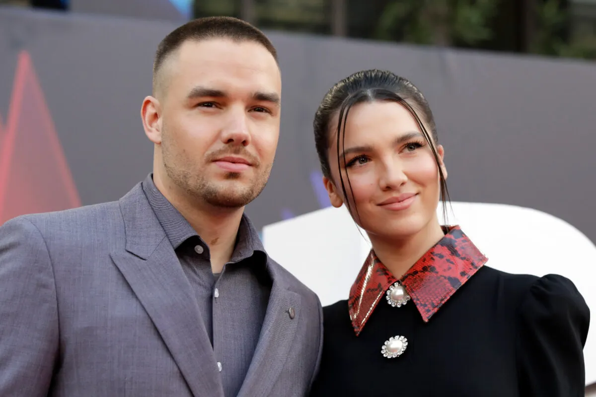 Liam Payne wears a gray suit and stands with Maya Henry, who wears a black shirt with a red snake collar.