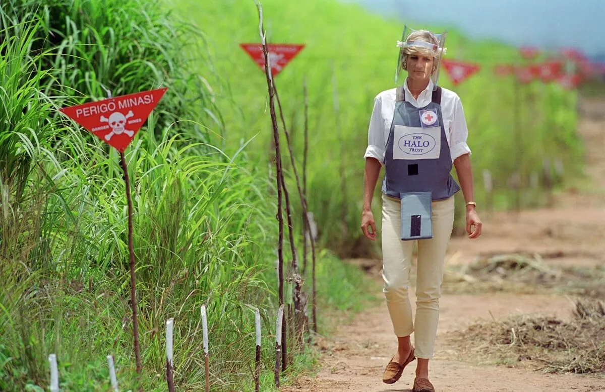 Princess Diana wearing protective body armor and a visor as she visits a landmine minefield in Huambo, Angola