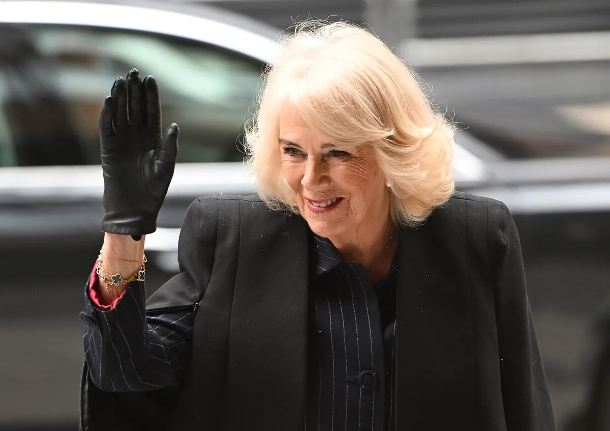 Queen Camilla waves to crowd during a visit to the Mulberry Academy in London