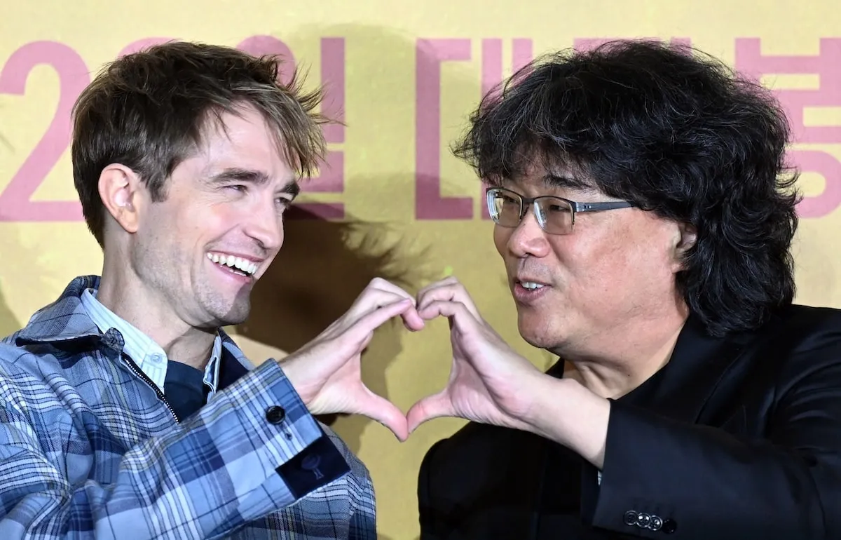 'Mickey 17' actor Robert Pattinson and director Bong Joon-ho form a heart with their hands and laugh together