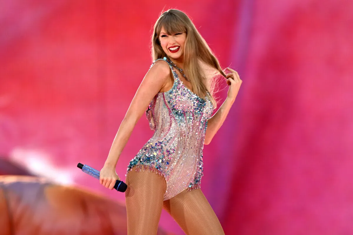 Taylor Swift wears a sparkling bodysuit and holds a microphone.