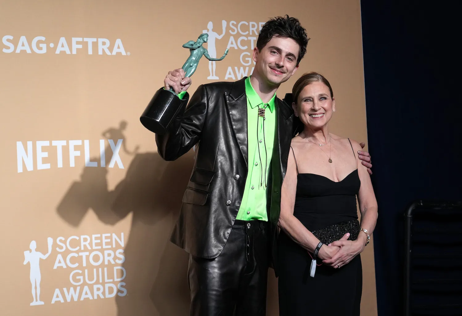 Timothée Chalamet posing with a SAG award with one arm around his mother, Nicole Flender