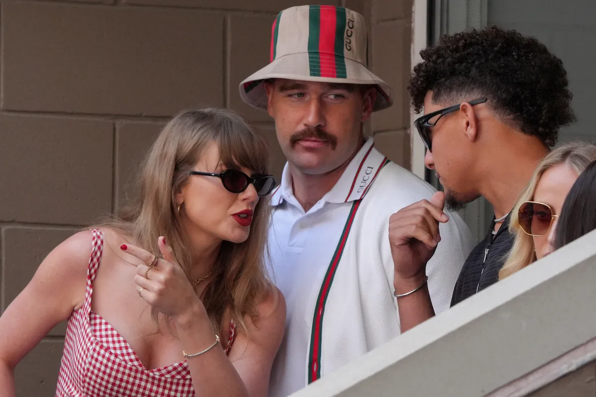 Taylor Swift leaning over Travis Kelce to speak to Patrick Mahomes at the US Open.